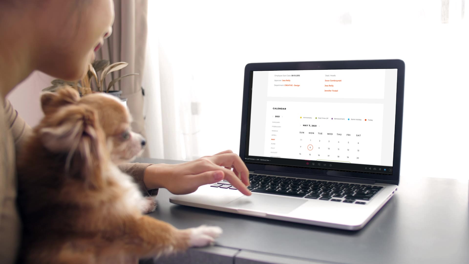 Woman with dog on her lap looking over PTO calendar in Leaf