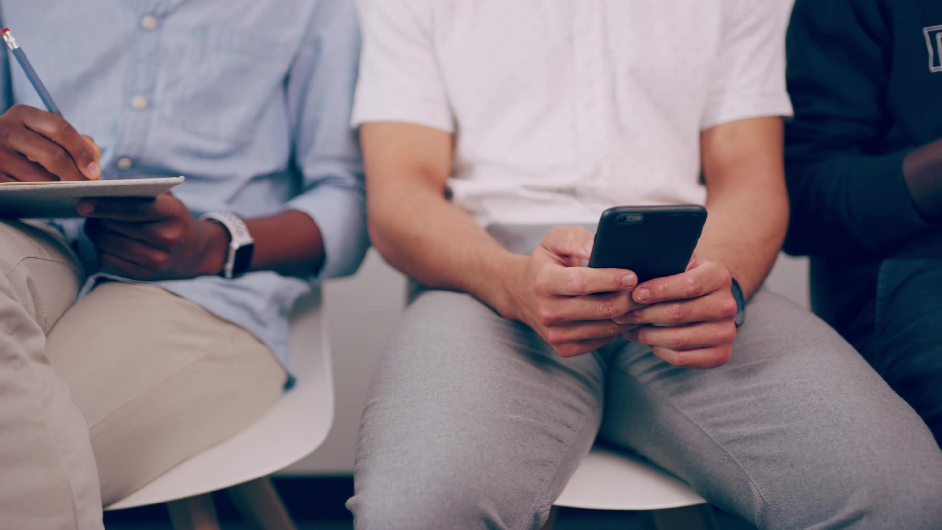 Two people sitting side by side using their phones